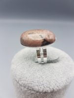 AN OVAL RHODONITE RING 25X18 with a pink stone on top.