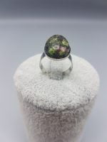 Un ANELLO DI ZOISITE RUBINO OVALE 18X13 con sopra una pietra verde.