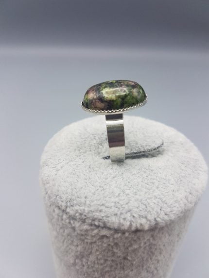 Un ANELLO DI ZOISITE RUBINO OVALE 18X13 con sopra una pietra verde.