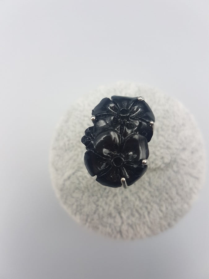 A black resin flower ring on a white surface.