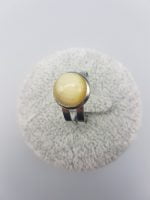 A ROUND YELLOW TIGER'S EYE RING with a yellow stone on it.