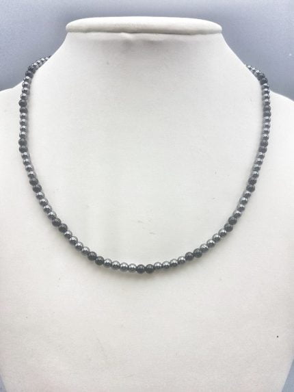 Una collana con perline COLLANA UOMO CON ONICE NERA ED EMATITE DA 4MM su manichino.