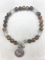 A bracelet with charm MEN'S BRACELET WITH TIGER'S EYE AND ROCK CRYSTAL WITH SCORPION PENDANT and tiger's eye beads.