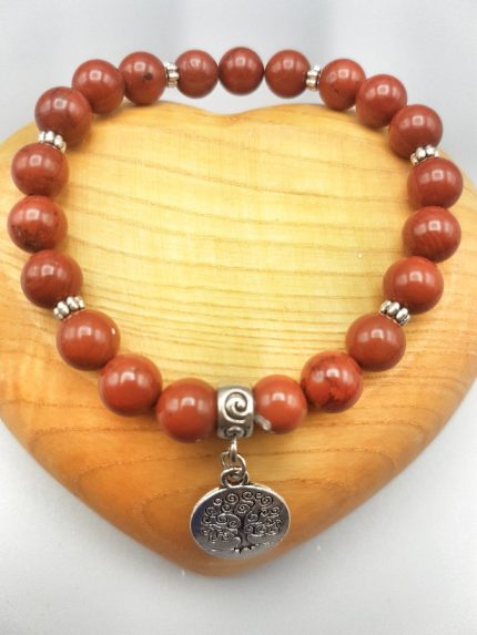 UN BRACCIALE DI DIASPRO ROSSO CON ALBERO DELLA VITA con grani di corallo rosso e charm in argento.