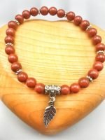 UN BRACCIALE DI DIASPRO ROSSO CON PIUMA con charm foglia e argento.