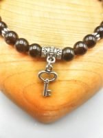 A black obsidian bracelet with a silver key pendant.