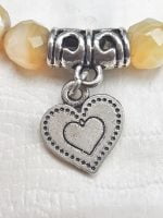 A bracelet with a heart-shaped pendant and yellow agate pearls.