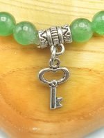 A green aventurine bracelet with a silver key pendant.