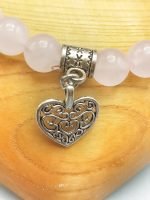 An 8mm rose quartz bracelet with a silver heart pendant.