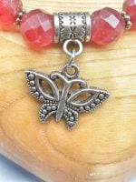 A RUBY JADE BRACELET AND BUTTERFLY PENDANT with butterfly pendant.