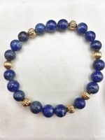 A LAPIS LAZULI BRACELET AND GOLDEN BALLS stroked with golden hues.