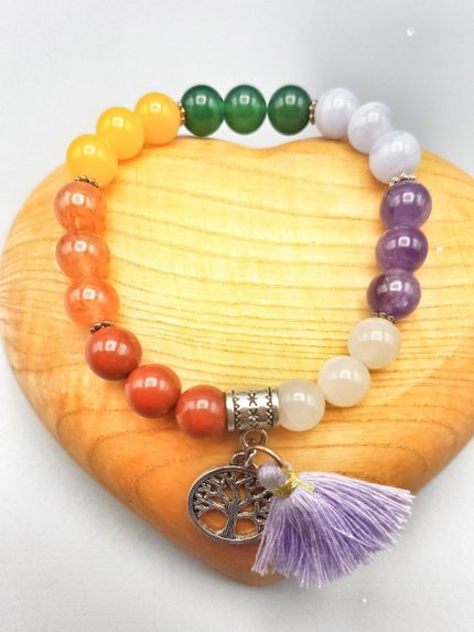 Un colorato BRACCIALE DEI SETTE CHAKRA CON CIONDOLO con nappina e charm albero della vita.