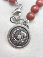 Una collana con perla BRACCIALE UOMO DI DIASPRO ROSSO ED EMATITE CON CIONDOLO DELLA VERGINE e charm in argento.
