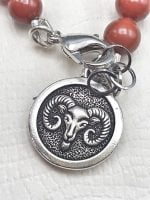 A MEN'S BRACELET WITH RED JASPER AND RAM PENDANT with a sheepskin on top.