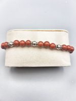 A bracelet with red jasper beads and silver beads.