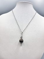 A SMALL ROUND TIGER EYE PENDANT with a small black bead.