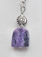 A sugilite pendant on a silver chain.