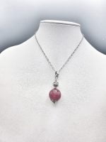 A necklace with a RUBY JADE PENDANT stone on it.