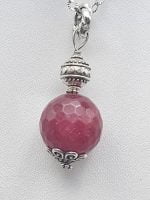 A ruby jade pendant on a silver chain.
