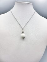 A spherical white agate pendant on a mannequin.