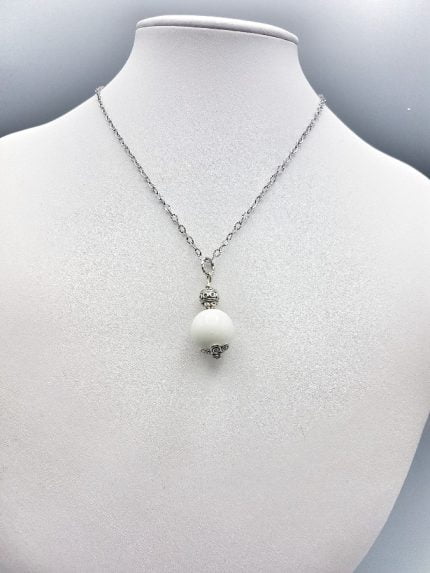 A spherical white agate pendant on a mannequin.