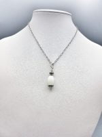 A WHITE AGATE BARREL PENDANT on a silver chain.