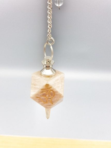 A necklace with a MOONSTONE PENDULUM AND OM symbol hanging.
