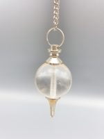 SPHERICAL ROCK CRYSTAL PENDULUM hanging from a silver chain.