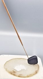 AN INCENSE BURNER SLICE OF WHITE AGATE is placed on top of a sheet of paper.