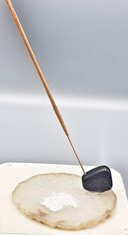 AN INCENSE BURNER SLICE OF WHITE AGATE is placed on top of a sheet of paper.