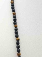 Collana A COLLANA UOMO CON ONICE NERA E OCCHIO DI TIGRE DA 4MM su superficie bianca.
