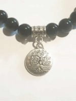 A BLACK TOURMALINE BRACELET WITH TREE OF LIFE with silver tree of life charm.
