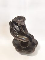 Un contenitore nero FONTANELLA CASCATA DI FUMO MANO DI BUDDHA con sopra un fiore.