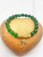 Un braccialetto BRACCIALE GIADA VERDE E CIONDOLO PALMA CON STRASS DORATO con un ciondolo palma dorato.