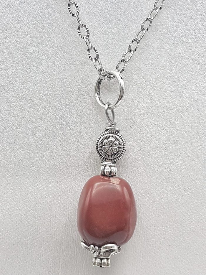 Un CIONDOLO DI DIASPRO ROSSO BARILOTTO su una catena d'argento.