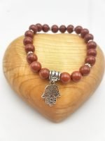 Un BRACCIALE DIASPRO ROSSO con un ciondolo argento a forma di mano di Fatima.