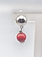 Descrizione: Un perlina di corallo rosso pende da un orecchino a clip con corallo.