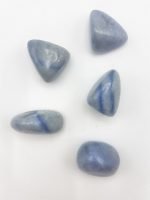 Four tumbled blue quartz stones on a white surface.