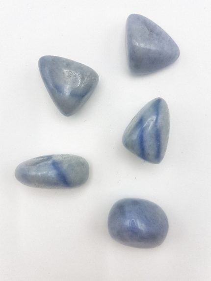 Four tumbled blue quartz stones on a white surface.