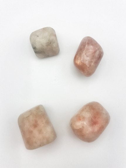 Tre pezzi di pietre rosa e bianche su una superficie bianca, raffiguranti PIETRA DEL SOLE BURATTATA.
