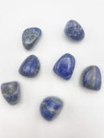 A cluster of TUMBLED LAPIS Lazuli stones on a white surface.