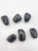 A group of black stones of Tumbled Obsidian on a white surface, called TUMBLED OBSIDIAN.