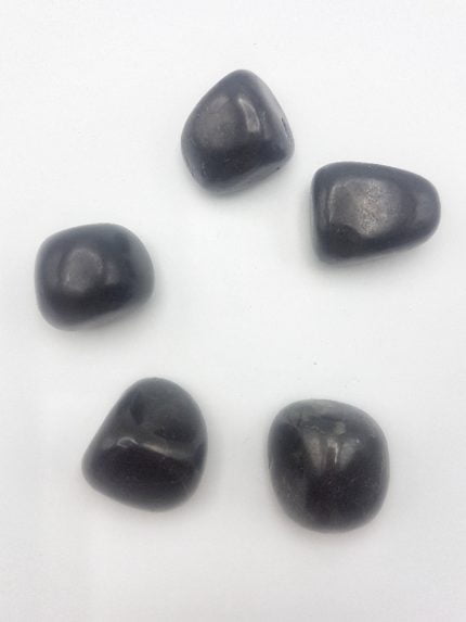 Un gruppo di pietre nere disposte su una superficie bianca, somiglianti alla Shungite Burattata.