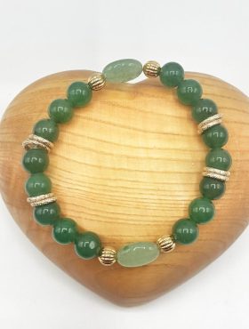 Un BRACCIALE AVVENTURINA VERDE DORATO su un cuore di legno dorato.