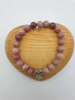 Un braccialetto di pietra rosa con un ciondolo d'argento.