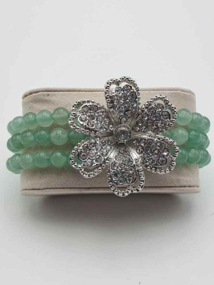 Un BRACCIALE DI AVVENTURINA VERDE E FIORE CON STRASS con un fiore brillante.