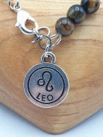 A bracelet with zodiac pendant and tiger's eye pearl, featuring a MEN'S BRACELET WITH ROCK CRYSTAL, TIGER'S EYE AND LION PENDANT.