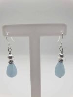A pair of teardrop angelite earrings on a stand.