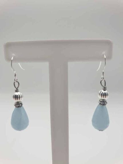 A pair of teardrop angelite earrings on a stand.