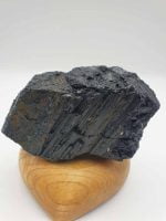 UN PEZZO DI TORMALINA NERA SCHORL 11 CM, detto anche Schorl, appoggiato su un supporto di legno.